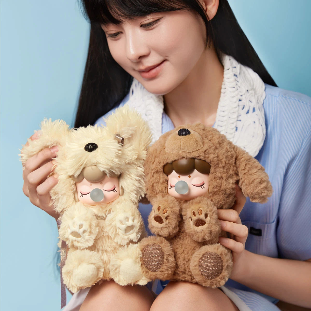 Person holding cream Yorkie and curly brown Teddy Nanci Puppy Club plush dolls side by side, showing sleeping faces, blue bubbles and embroidered paw pads.