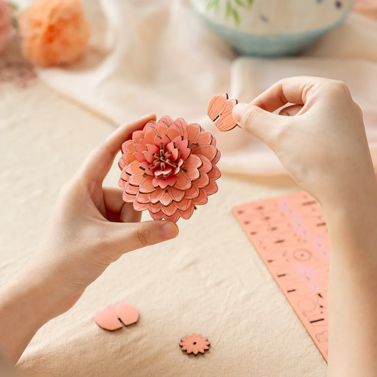Pink Dahlia TW131 assembly scene with hands arranging the wooden flower