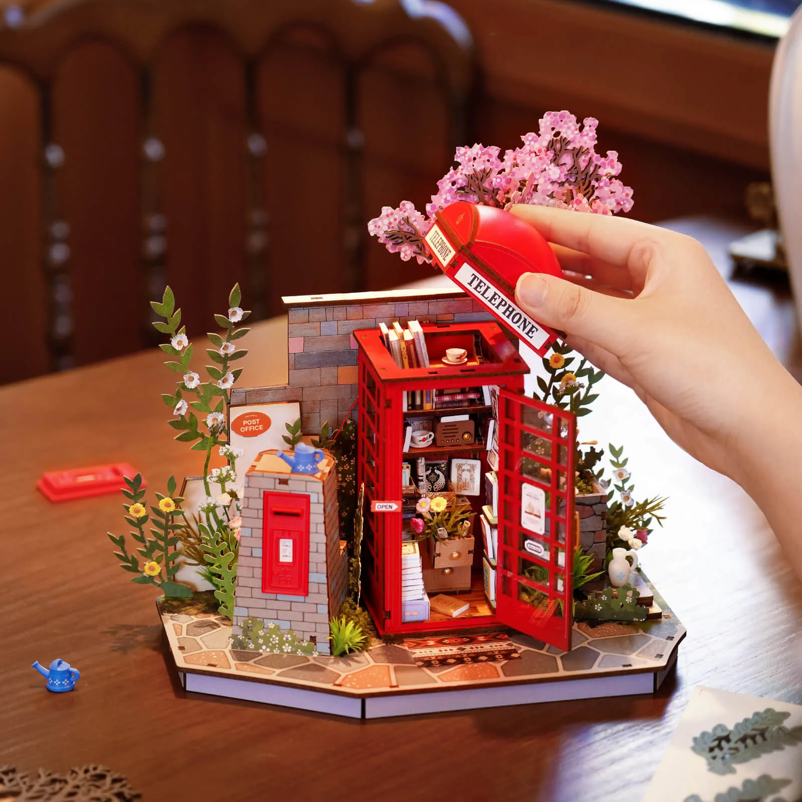 Hands placing books inside Blossom Book Booth red telephone booth model