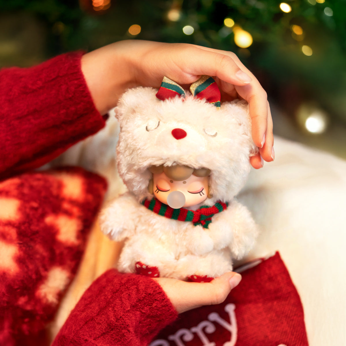 Nanci Christmas Bear plush pendant being held by hand in a festive scene