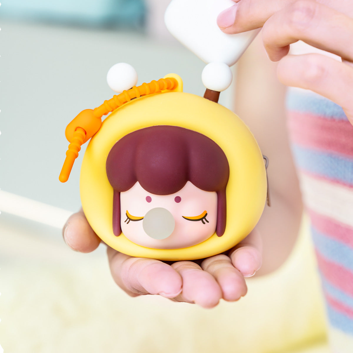 Baby Nanci Fluffy Party yellow bee earphone case held in hand