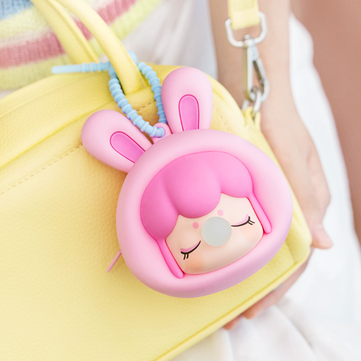 Baby Nanci Fluffy Party earphone case hanging from a yellow handbag