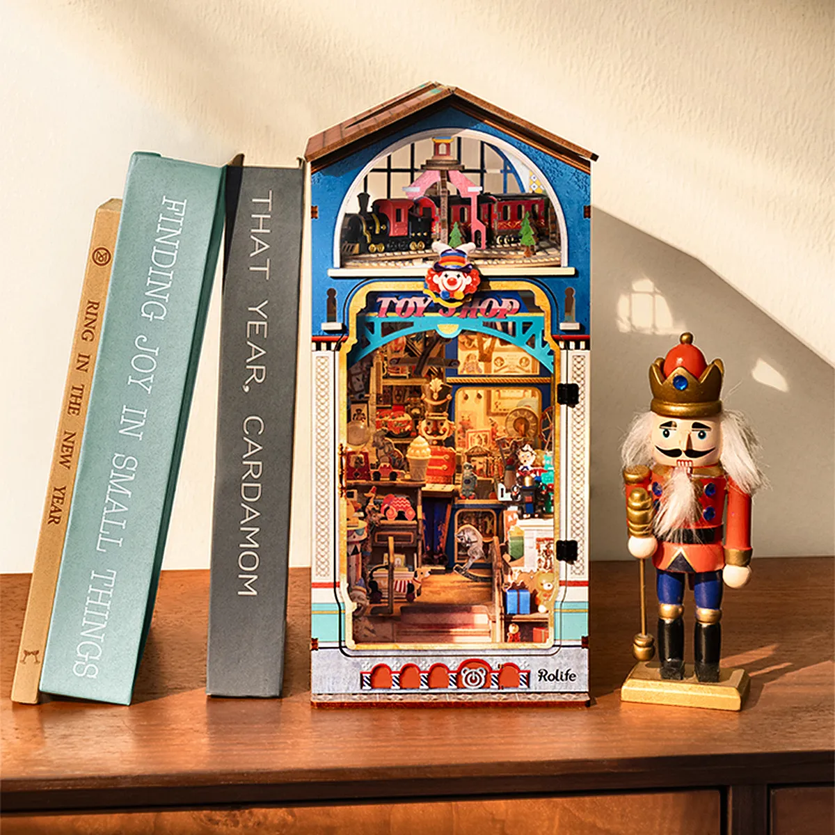 Rolife Treasure Toy Shop DIY Book Nook displayed beside books and nutcracker