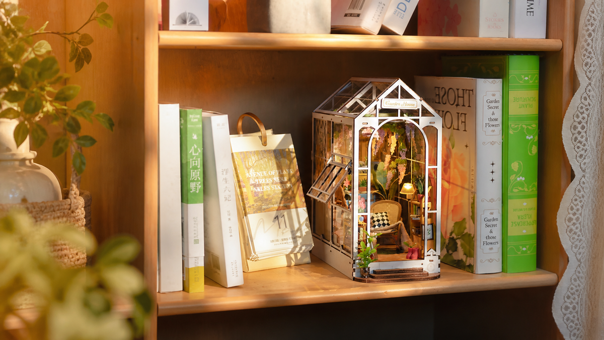 Rolife Holiday Garden House TGB06 glowing between books on a warm botanical bookshelf